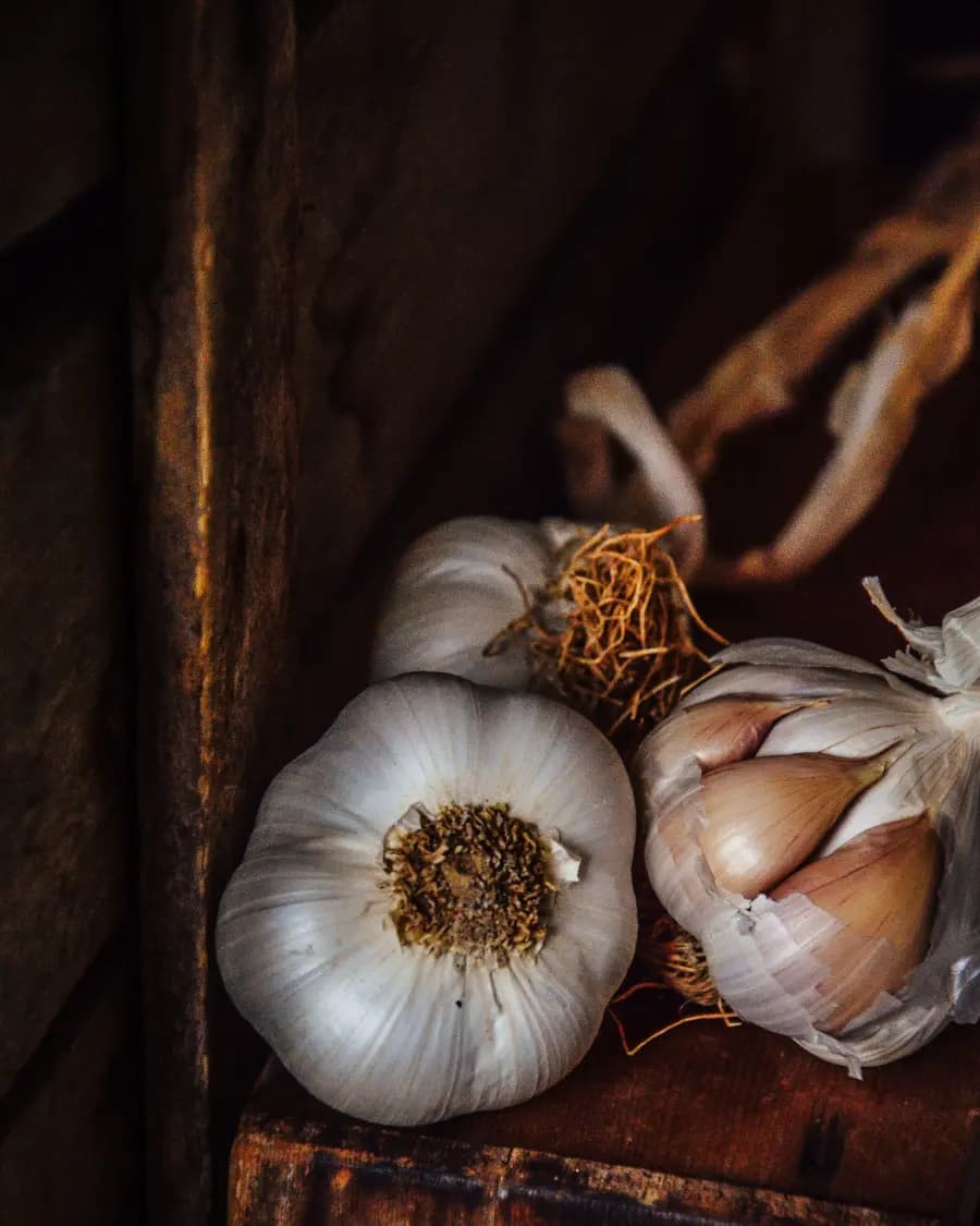 Fresh garlic bulbs on aged wood, the raw ingredient behind every allium. formula
